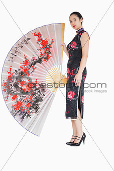 Woman in kimono standing with large silk fan