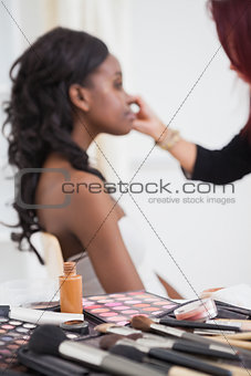 Table full of makeup with woman getting made over