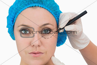Plastic surgeon writing on woman's face