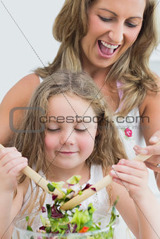 Close up of mother and daughter during mixing salad