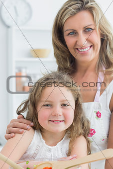 Mother hugging daughter and making salad