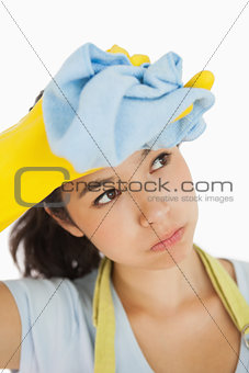 Woman wiping her brow wearing rubber gloves