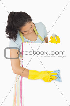 Smiling woman in apron wiping white surface