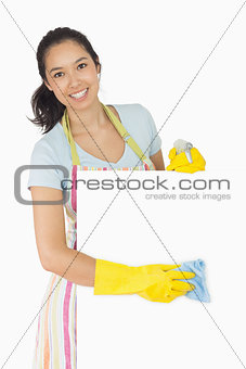 Cheerful woman wiping down white surface