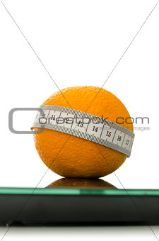 Closeup of orange on a scale wrapped with measuring tape