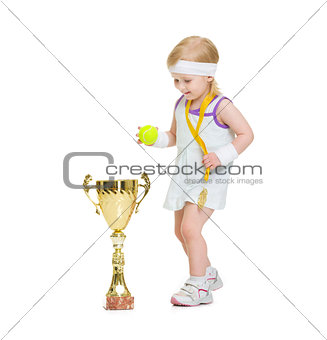 Baby in tennis clothes with medal and goblet
