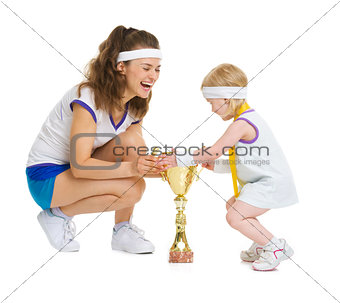 Mother and baby in tennis clothes with medal and goblet