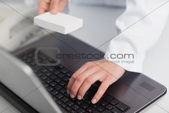 Pharmacist typing on a computer and holding a box of pills