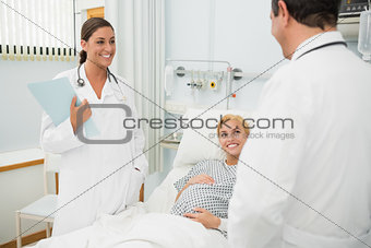 Female and male doctors standing next to a patient