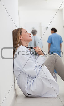 Thoughtful doctor sitting on a hallway
