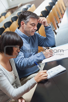 Man and woman taking notes during lecture