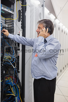 Man fixing wires while making a phone call
