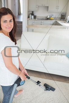 Smiling woman hoovering the rug