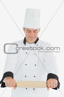 Man in chef uniform using rolling pin