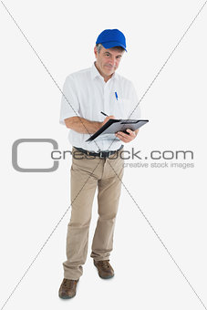 Portrait of mature delivery man writing on clipboard