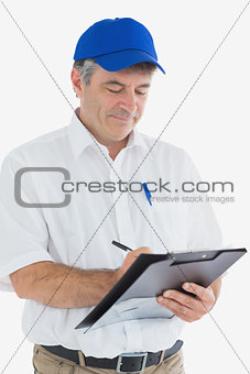 Mature delivery man writing on clipboard