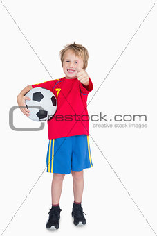 Portrait of boy with football gesturing thumbs up