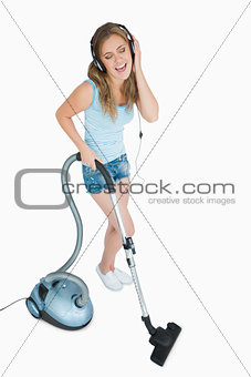 Woman enjoying music over headphones while vacuuming