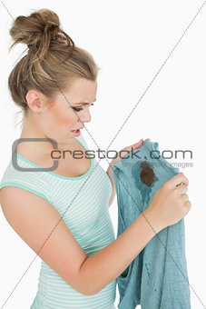 Displeased young woman looking at stained shirt