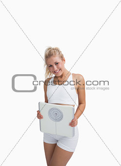 Portrait of young happy woman holding weighing scales