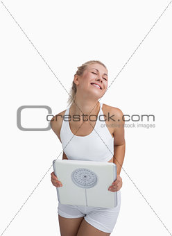 Excited young happy woman holding weighing scales