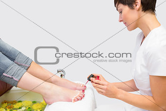 Woman applying nail varnish to toe nails at spa center