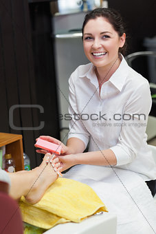 Woman buffering toe nails at spa center