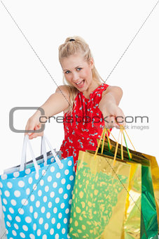 Cute excited young woman holding out shopping bags