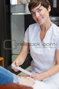 Portrait of nail technician filing womans toe nails