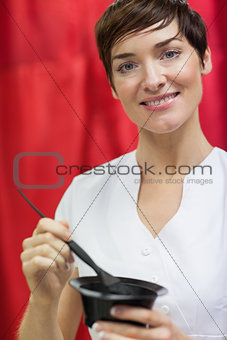 Portrait of woman mixing hair color over red backdrop