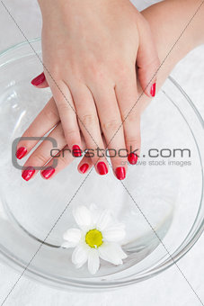 Red painted finger nails with flower in bowl