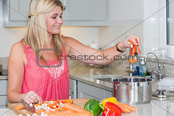 Young woman putting vegetables in the pot