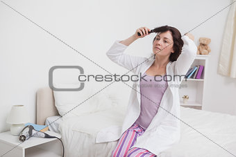 Young woman brushing hair in bed
