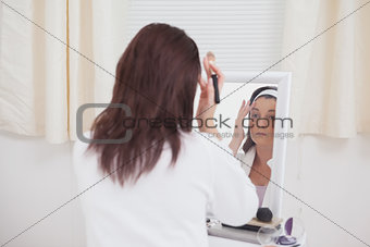 Young woman putting on makeup