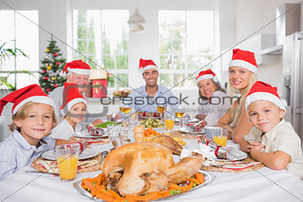 Happy family wearing santa hats around the dinner table