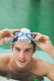 Smiling man taking off goggles