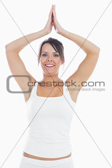 Portrait of woman in sportswear joining hands over head