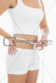 Midsection of woman measuring waist