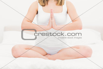 Woman sitting in praying position on bed