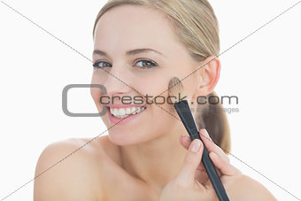 Portrait of smiling young woman putting on makeup