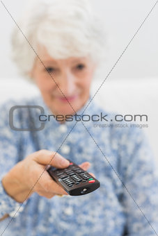 Elderly cheerful woman using the remote