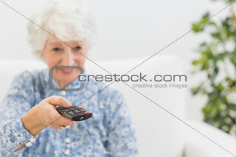 Elderly smiling woman using the remote