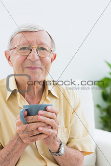 Elderly man looking at camera with a cup