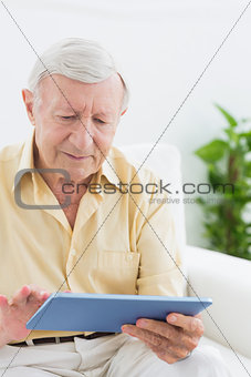 Elderly focused man using a digital tablet