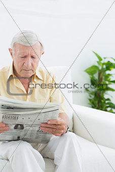 Elderly serious man reading newspapers