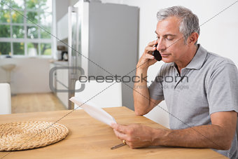 Man calling and reading a sheet of paper