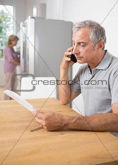 Mature man calling with a sheet of paper
