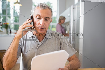 Focused man calling with a sheet of paper
