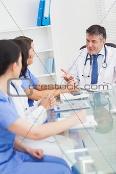 Meeting between a doctor and three nurses smiling