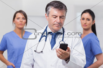 Doctor looking at phone with his team of nurses